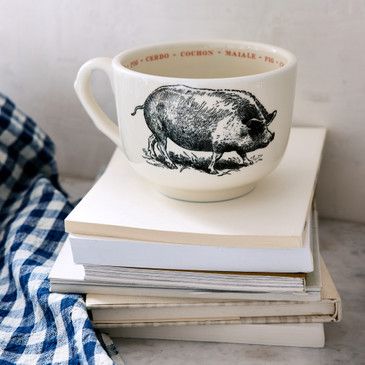 Mug with pig design on a stack of books next to a checkered cloth