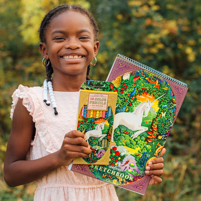 Young girl holding a colorful notebook with unicorn design and a pencil case.