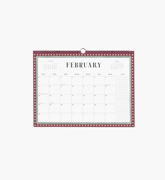 A hanging February calendar page with a burgundy border, white center, and printed monthly grid layout, shown against a light gray background.