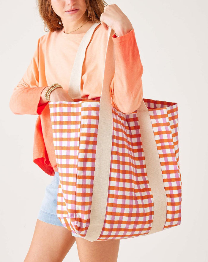 Person holding a large checkered bag with a plain background