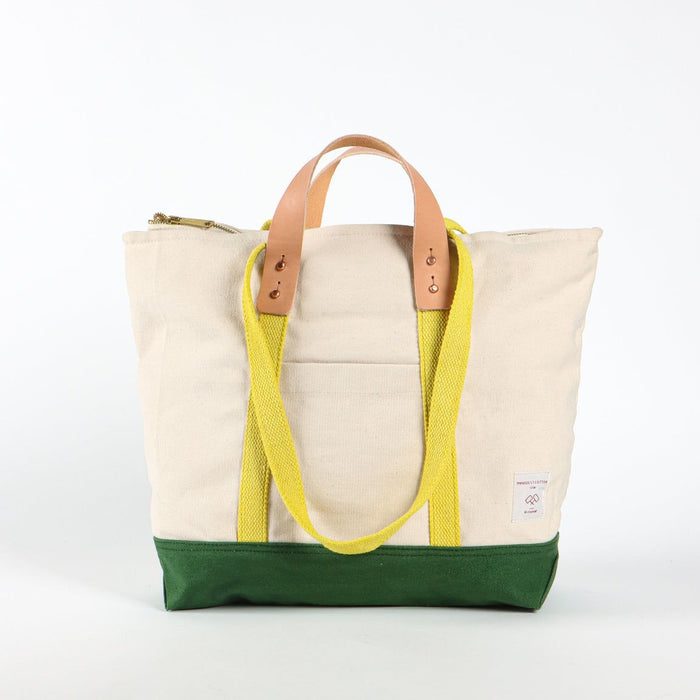 Beige tote bag with yellow strap and green bottom section on a white background