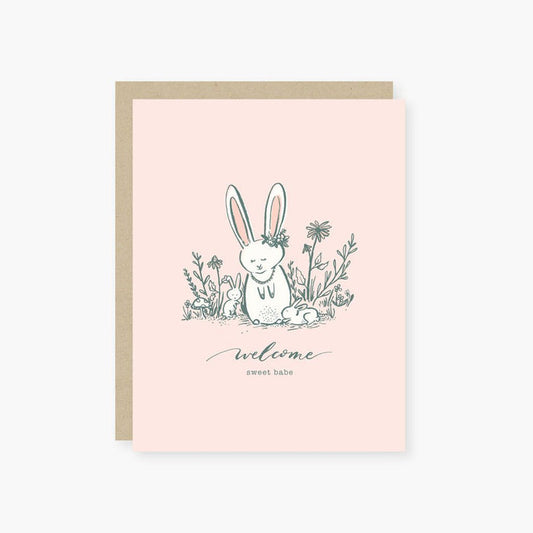 Greeting card with a bunny illustration and 'welcome sweet babe' text on a pink background
