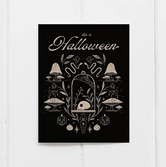 A vertical black art print with cream-colored Halloween illustrations and the words 'also to Halloween' at the top, displayed against a white wood plank background.