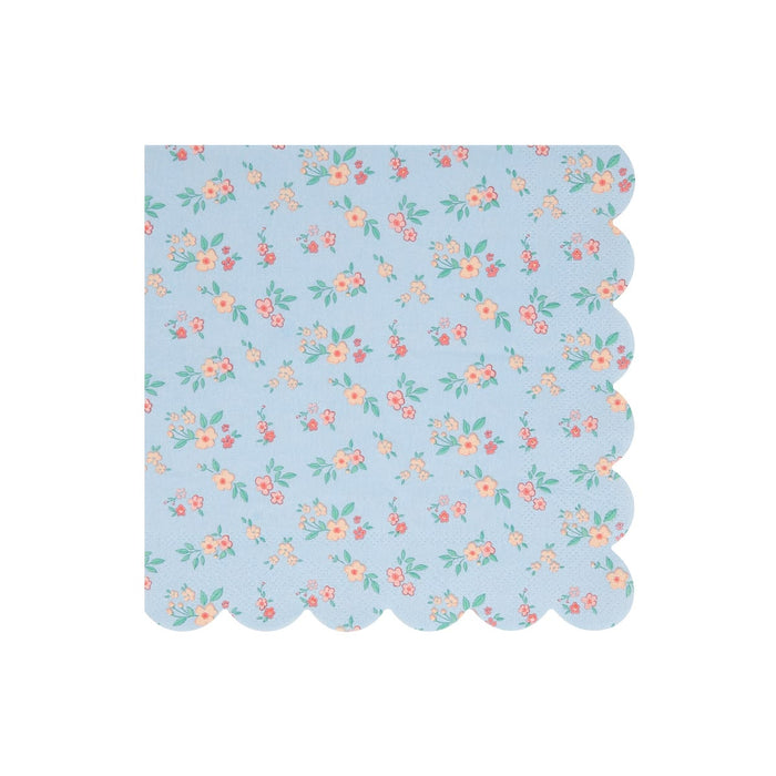 A square paper napkin with a scalloped edge, featuring a light blue background with a delicate repeating floral pattern in pink, orange, and green.